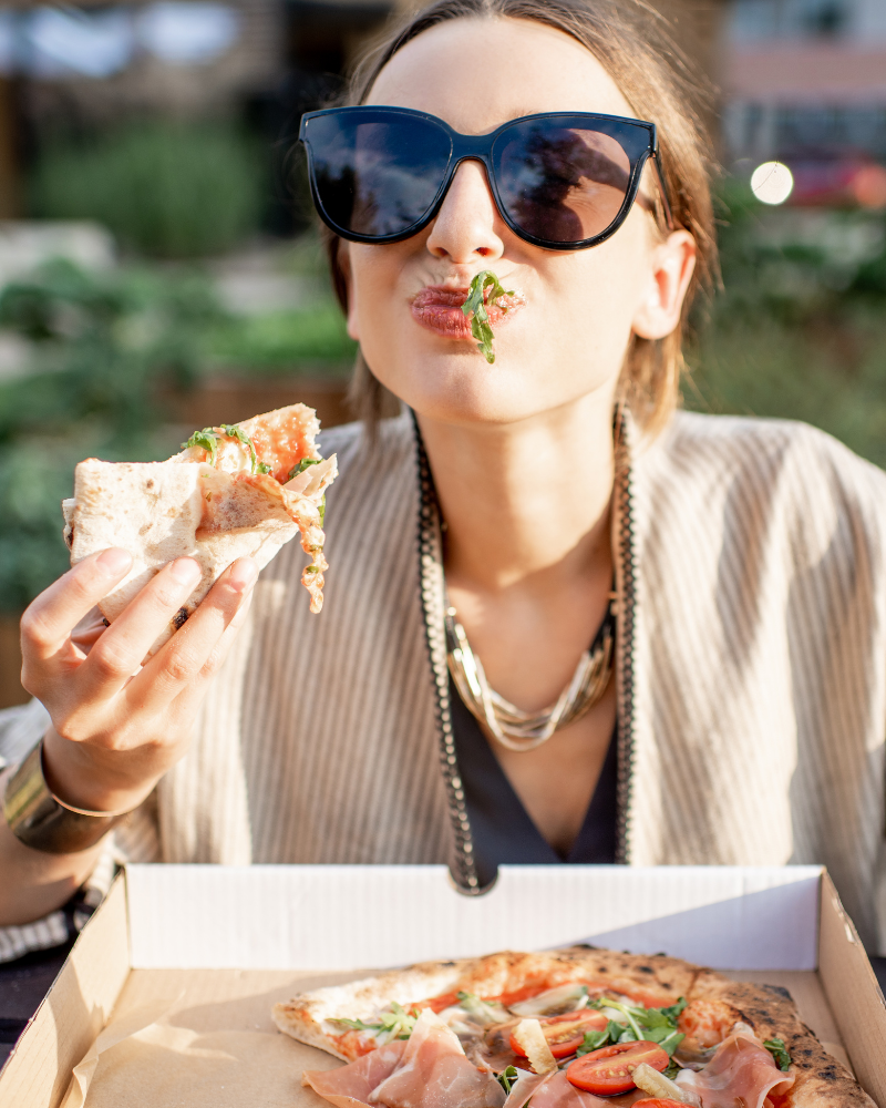 A girl eating pizza after having taken off her clear smiles club aligners.
